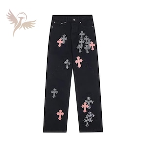 May include: Black denim jeans featuring a straight-leg cut with a button fly closure. The fabric is decorated with multiple cross-shaped patches in two distinct styles: solid light pink crosses and black-and-white checkered pattern crosses.