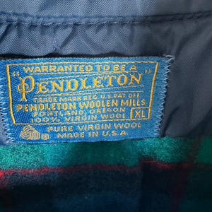 May include: Close-up of a blue Pendleton label, stitched onto a wool garment. The label reads "WARRANTED TO BE A PENDLETON" and includes text about the Pendleton Woolen Mills in Portland, Oregon. The garment is XL and made in the U.S.A.