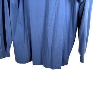 Pu&ograve; includere: Una maglia blu a maniche lunghe con scollo rotondo e polsini a coste sui polsi. Il capo &egrave; realizzato in un tessuto semplice con un colore uniforme, caratterizzato da una vestibilit&agrave; standard con un orlo dritto sul fondo.