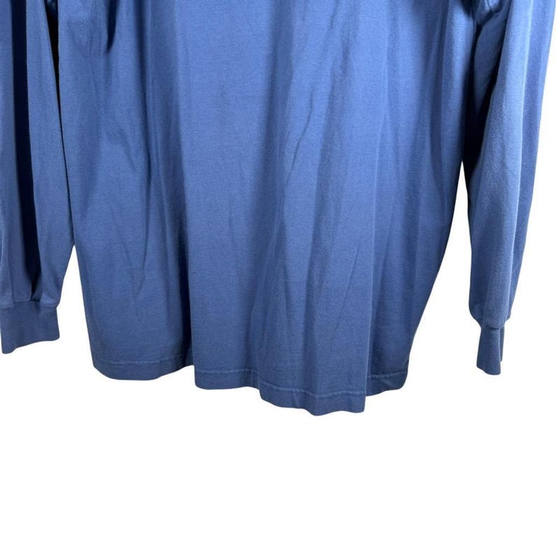 Pu&ograve; includere: Una maglia blu a maniche lunghe con scollo rotondo e polsini a coste sui polsi. Il capo &egrave; realizzato in un tessuto semplice con un colore uniforme, caratterizzato da una vestibilit&agrave; standard con un orlo dritto sul fondo.