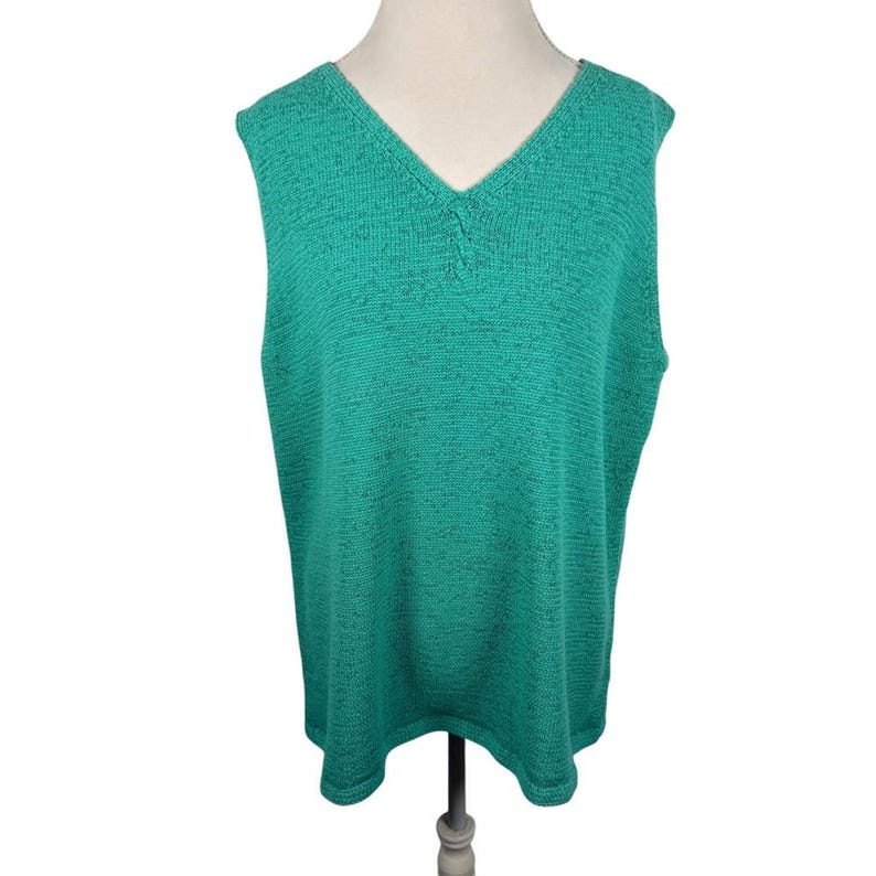 Puede incluir: Un chaleco sin mangas de color verde azulado con cuello en V. El tejido de punto tiene un aspecto texturizado y un sutil estampado moteado. El chaleco se muestra en un maniqu&iacute;, mostrando su forma y dise&ntilde;o. Una prenda casual y c&oacute;moda.