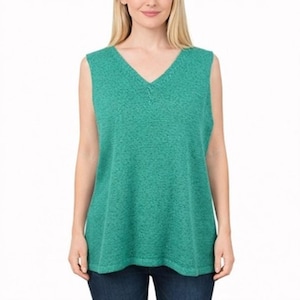 Puede incluir: Una blusa sin mangas de color verde azulado con cuello en V. La tela tiene un aspecto texturizado. La blusa se usa con jeans azul oscuro. La modelo es de piel clara y tiene el pelo rubio.