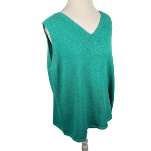 Puede incluir: Un chaleco sin mangas de color verde azulado con cuello en V. El chaleco tiene un patr&oacute;n de punto texturizado y se muestra en un maniqu&iacute;. La prenda es de color liso y parece estar hecha de un material suave.