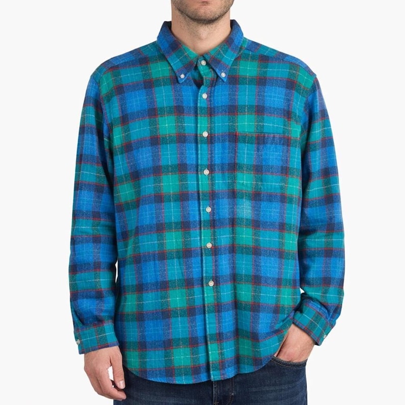 May include: A long-sleeved plaid shirt in shades of blue, green, and red. The shirt has a button-down collar, a chest pocket, and buttoned cuffs. The plaid pattern is a classic design.