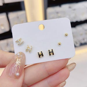 May include: A set of three ceramic mugs with a speckled, matte finish. The mugs are in shades of cream, light gray, and dark gray. Each mug has a simple, minimalist design, perfect for coffee or tea.