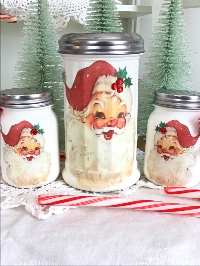 May include: Set of three white ceramic Santa Claus sugar dispensers with red and green accents. The dispensers have a vintage look and are perfect for adding a festive touch to your kitchen.