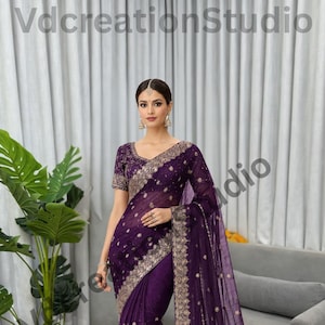 Peut inclure: Un sari formel violet avec des broderies et des ornements dorés complexes. Le sari présente un tissu transparent et fluide avec une bordure détaillée et un chemisier à manches courtes assorti. Le texte "VdcreationStudio" est inclus.