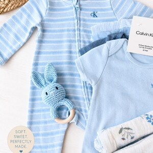 branded Calvin klein baby gift set, including Calvin Klein sleeper and 4 bodysuits. it also includes a blue baby rattle and muslin clothes. branded baby boy gift ready gift set. baby boy gift set under 50 dollars. baby shower boy gift set. baby boy essentials