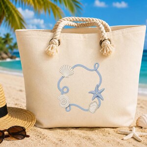 Puede incluir: Un bolso tote de lona color crema con asas gruesas de cuerda trenzada sujetas con ojales metálicos. La parte frontal del bolso muestra un diseño estampado de un marco de cuerda azul decorado con varias conchas marinas blancas y azules y una estrella de mar.