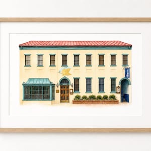 Peut inclure: Une illustration à l'aquarelle encadrée d'un bâtiment à deux étages avec une façade crème, un toit en métal rouge et des bordures bleu sarcelle. Le bâtiment présente une grande baie vitrée, une porte centrale en bois et un panneau bleu.