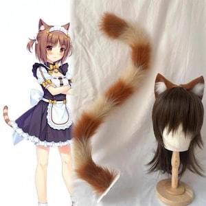 May include: A cosplay set featuring a long, fluffy cat tail with brown and cream stripes, a matching set of cat ears, and a cartoon illustration of a character in a maid outfit. The tail is approximately 24 inches long.