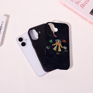May include: A black phone case featuring a cartoon character in a yellow coat and blue hair, with various small graphic elements. A white phone and a black phone case are next to it. The phone cases are on a white surface.