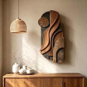 May include: A wall-mounted sculpture featuring layered dark textured panels and smooth, curved light wood elements. The piece has an elongated vertical shape with a circular top section and overlapping wave-like wooden forms that create depth.