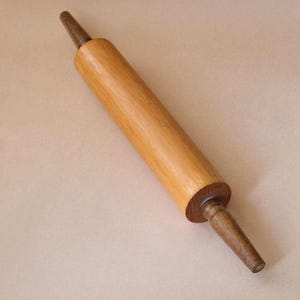 Può includere: Un mattarello in legno con un corpo marrone chiaro e manici marrone scuro. Il mattarello è fatto di legno ed è progettato per stendere l'impasto per la cottura. Il mattarello è lungo circa 40 cm.