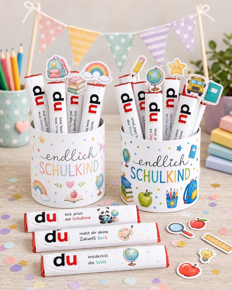 May include: Two white cylindrical containers decorated with colorful school-themed illustrations and the text "endlich SCHULKIND". Each container holds several white chocolate bars labeled "du" with various school-themed toppers and text.