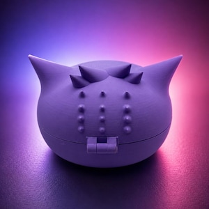 May include: A lavender-colored, spherical container with a hinged closure. The container has a series of small, raised bumps and three pointed protrusions on top. The background transitions from blue to pink.