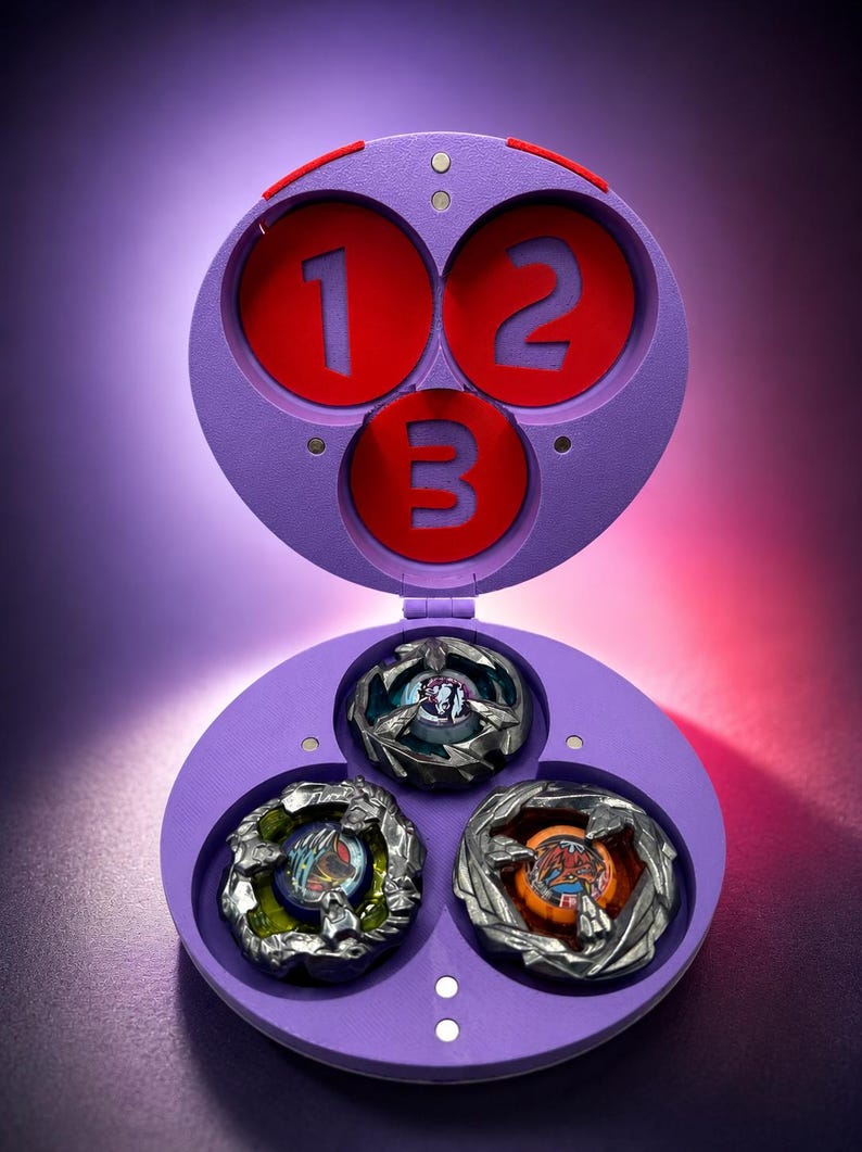 May include: A purple toy case with three red circles labeled 1, 2, and 3. The case is open, revealing three spinning tops with metallic silver and colorful designs. The background is a gradient of purple and red.