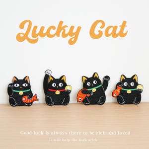 May include: Four black cat embroidered patches with yellow ears, green or red collars, and gold bells. Each cat holds a red fish or a gold coin. The text Lucky Cat appears at the top, and the text Good luck is always there to be rich and loved. It will help the luck stick appears at the bottom.