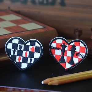May include: Two heart-shaped embroidered patches featuring chess themes. The left patch has a black and white chequered pattern with red and black chess pieces. The right patch has a red and white chequered pattern with black chess pieces and the text Queen and King.