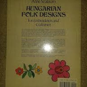 以下が含まれることがあります： アン・サカヴァリー著「Hungarian Folk Designs」というタイトルの本。表紙は薄いベージュで、タイトルは濃い青色、「For Embroiderers and Craftsmen」というサブタイトルが書かれています。裏面には花のイラストとバーコードが描かれています。