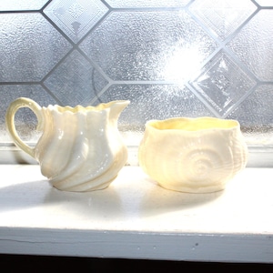 Puede incluir: Un juego de tres tazas de cerámica con acabado mate moteado. Las tazas son de color crema, gris claro y gris oscuro. Cada taza tiene un diseño simple y minimalista.