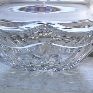 May include: A clear glass bowl with a cut crystal design. The bowl has a wide, round base and a slightly flared rim.