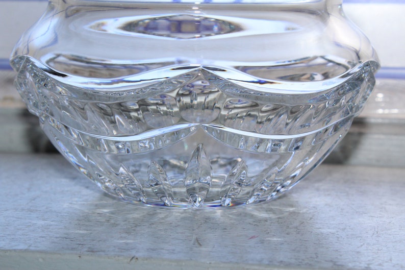 May include: A clear glass bowl with a cut crystal design. The bowl has a wide, round base and a slightly flared rim.