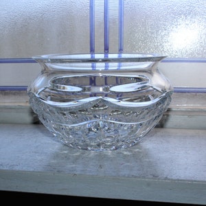 May include: A clear glass bowl with a cut crystal design. The bowl is sitting on a windowsill.