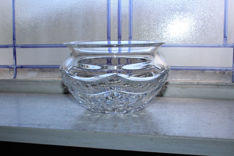 May include: A clear glass bowl with a cut crystal design. The bowl is sitting on a windowsill.