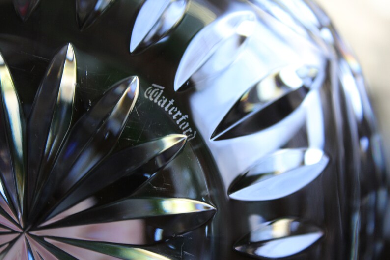 May include: Close-up of a Waterford crystal bowl with a detailed, intricate pattern. The word "Waterford" is etched into the bottom of the bowl.