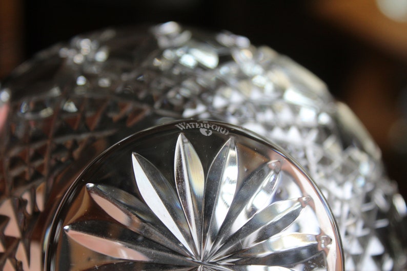 Puede incluir: Primer plano de un cuenco de cristal transparente con un dise&ntilde;o de estrella en la base. La palabra "WATERFORD" est&aacute; grabada en el borde. El cuenco tiene un patr&oacute;n de corte de diamante.