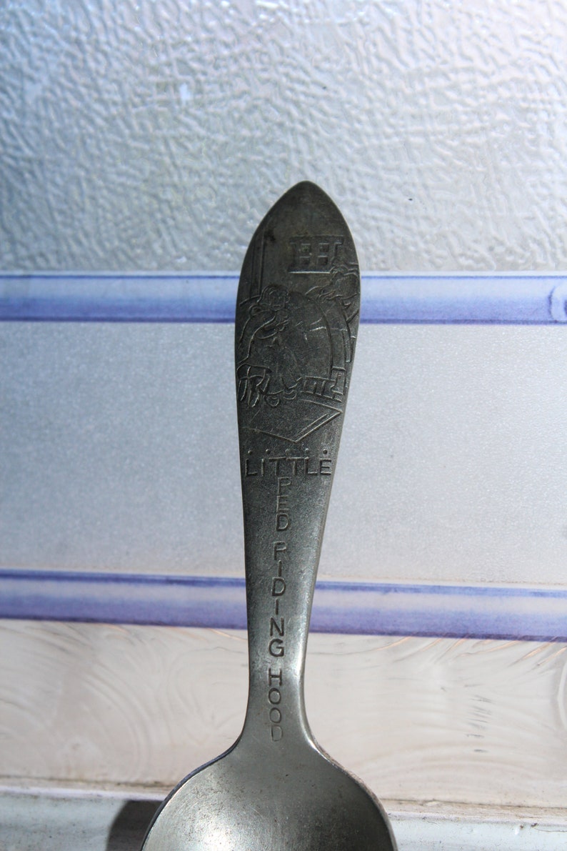 May include: A silver spoon with a design of Little Red Riding Hood and the words "Little Red Riding Hood" engraved on the handle.
