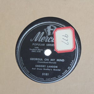 May include: Black and silver 78 RPM record with the title "Georgia On My Mind" by Snooky Lanson and Owen Bradley's Quartet. The record is from the Mercury Record Corporation, Chicago, Illinois, and is part of the Popular Series.