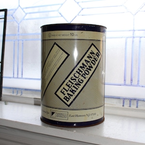 May include: A white and blue 10-pound can of Fleischmann's Baking Powder. The can has a striped design and the text "Fleischmann's Baking Powder" in blue letters. The can also has the text "NABISCO BRANDS" and "East Hanover NJ 07936".