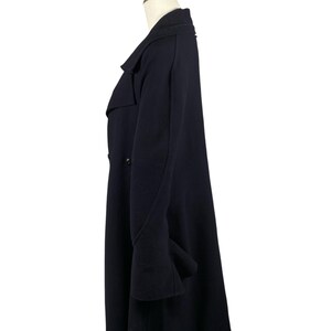 May include: A navy blue overcoat with a double-breasted design. The coat features a notched lapel, long sleeves, and a knee-length hem. The coat is displayed on a mannequin against a white background.