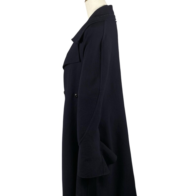 May include: A navy blue overcoat with a double-breasted design. The coat features a notched lapel, long sleeves, and a knee-length hem. The coat is displayed on a mannequin against a white background.