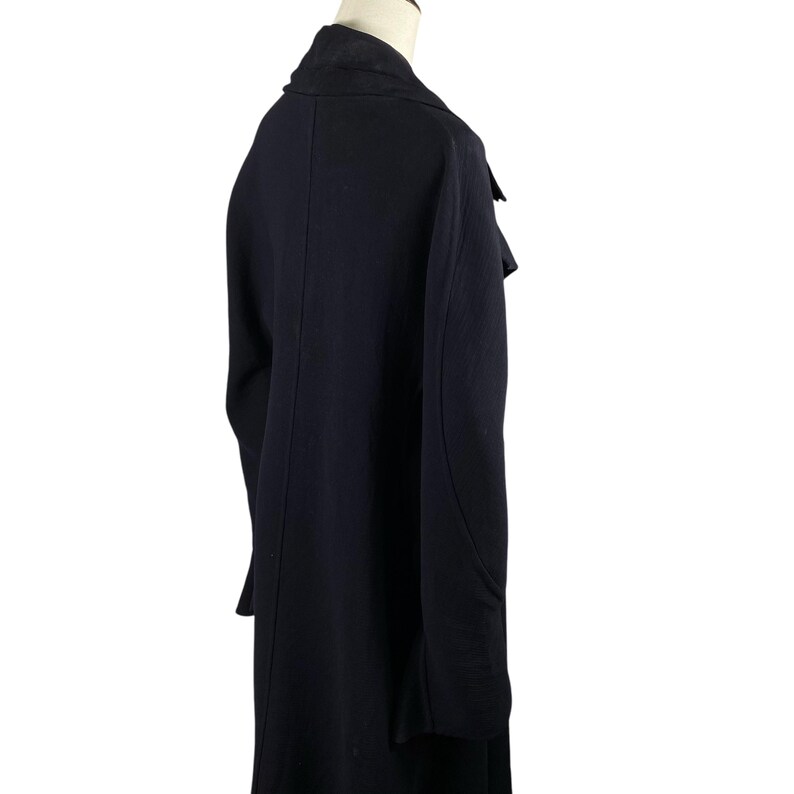 May include: A long, dark navy blue coat with a notched lapel and a contrasting black collar. The coat has a tailored fit and a classic design, suitable for various occasions.
