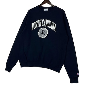 May include: Navy blue Champion sweatshirt with the words "NORTH CAROLINA" in white arched lettering. Below the text is a white circular emblem with text that reads "UNIVERSITY OF NORTH CAROLINA CHAPEL HILL".