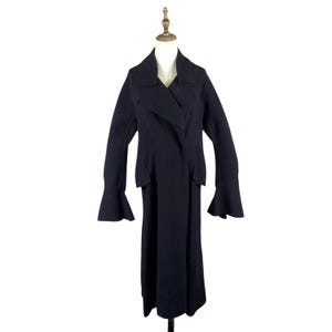 May include: A long, dark navy coat with a unique design. The coat features a wrap-style front, wide lapels, and flared sleeves. It is displayed on a mannequin against a white background, showcasing its full length and tailored silhouette.