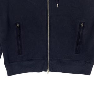 May include: Navy blue zip-up hoodie with two zippered pockets and a drawstring hood. The jacket has a full-length zipper and ribbed cuffs and hem. The fabric appears to be a soft, textured material.