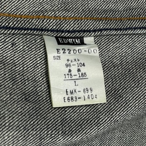 Puede incluir: Primer plano de una tela vaquera con una etiqueta. La etiqueta dice "EDWIN" e incluye informaci&oacute;n de tallas, con medidas de pecho de 96-104 cm y medidas de altura de 175-185 cm. La talla es L.