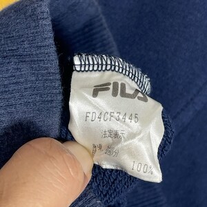 May include: A navy blue garment featuring a white interior fabric care label. The label displays the FILA brand name in black text, the alphanumeric code FD4CF3445, and Japanese characters. The fabric has a ribbed texture along the top edge.