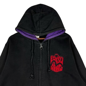 May include: Black zip-up hoodie with a purple-lined hood. The hoodie features a red embroidered design on the chest. The zipper has a decorative pull. The hoodie is made of a soft material.