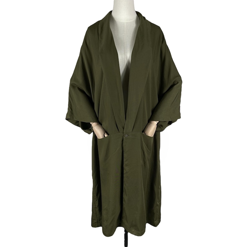Puede incluir: Bata estilo kimono verde oliva con un ajuste relajado. La bata presenta un cuello chal, mangas largas y dos bolsillos delanteros. Un cierre de bot&oacute;n &uacute;nico se encuentra en la cintura. La bata se exhibe en un maniqu&iacute;.