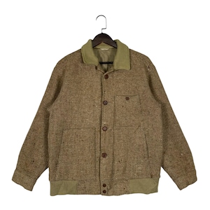 May include: A brown tweed jacket with a light green corduroy collar and cuffs. The jacket has two front pockets, brown buttons, and is hanging on a black hanger. The jacket is a medium size.