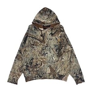 Puede incluir: Sudadera con capucha de camuflaje con cordón y un pequeño logotipo en el pecho. La sudadera presenta un patrón marrón y verde, con un forro interior de color canela en la capucha.