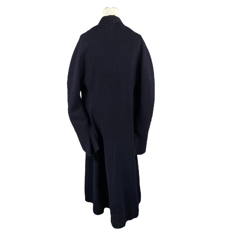 May include: A long, navy blue coat with a classic design. The coat is displayed on a mannequin, showcasing its full length and tailored silhouette. The coat features a simple, elegant style, suitable for various occasions.
