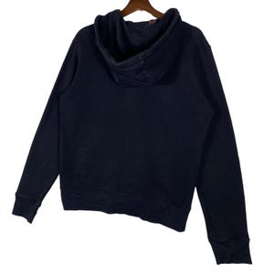 May include: A navy blue hoodie with a drawstring hood and long sleeves. The sweatshirt is made of a soft material and is hanging on a wooden hanger. The back of the hoodie is visible.