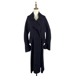 May include: A long, dark navy blue coat with a wide lapel collar and long sleeves. The coat is displayed on a mannequin and has a flowing, floor-length design. The coat's fabric appears to be a medium-weight material.