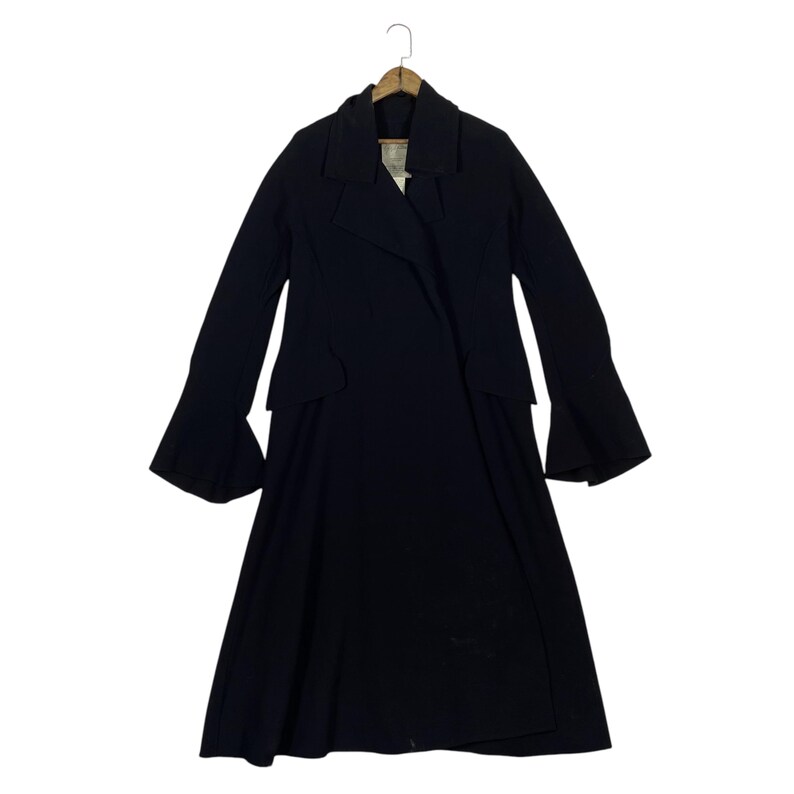 May include: A long, black coat with a flared skirt and wide sleeves. The coat has a double-breasted design with a notched collar and is hanging on a wooden hanger.